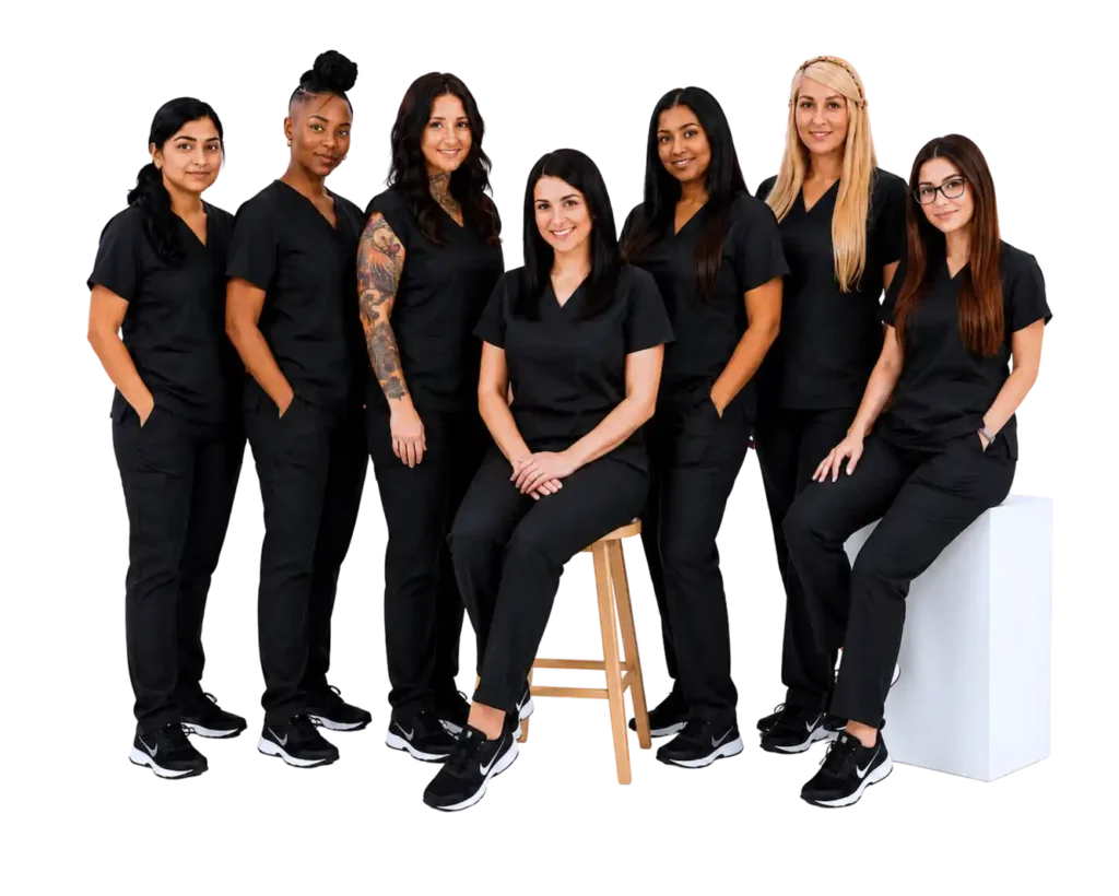 Seven women in black scrubs pose together, showcasing teamwork and professionalism in a healthcare setting.