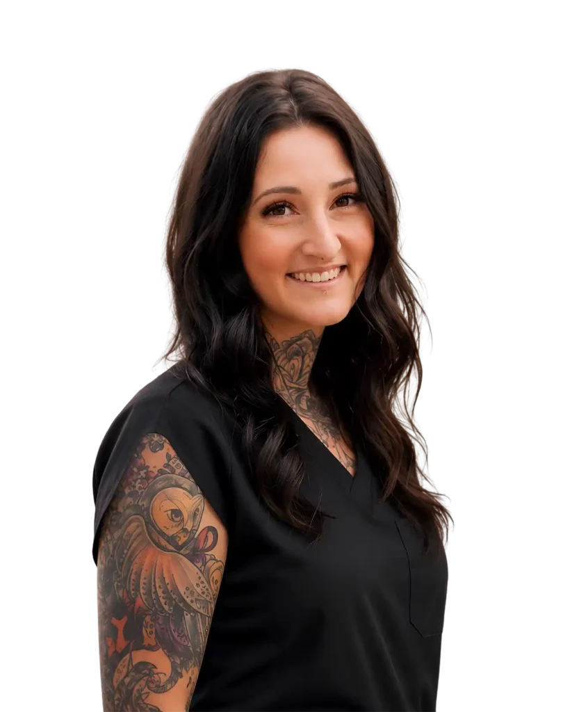 Smiling woman with long dark hair and colorful tattoos on her arm, wearing a black top, on a black background.